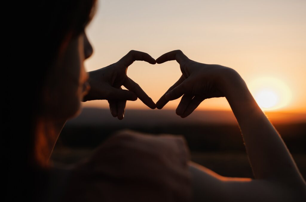 Hands shape heart. Little girl make sign love hands sunset. Small kid draw heart hands against sky