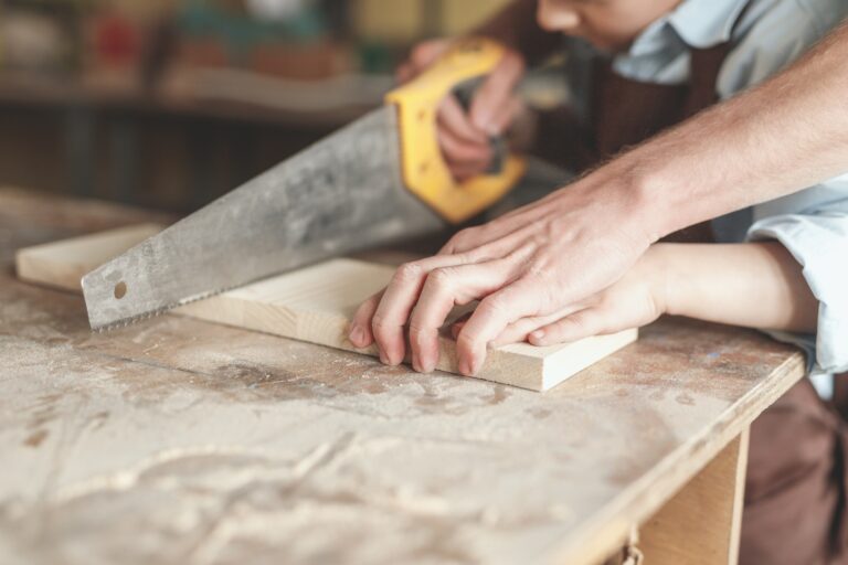 Father and son sawing a board